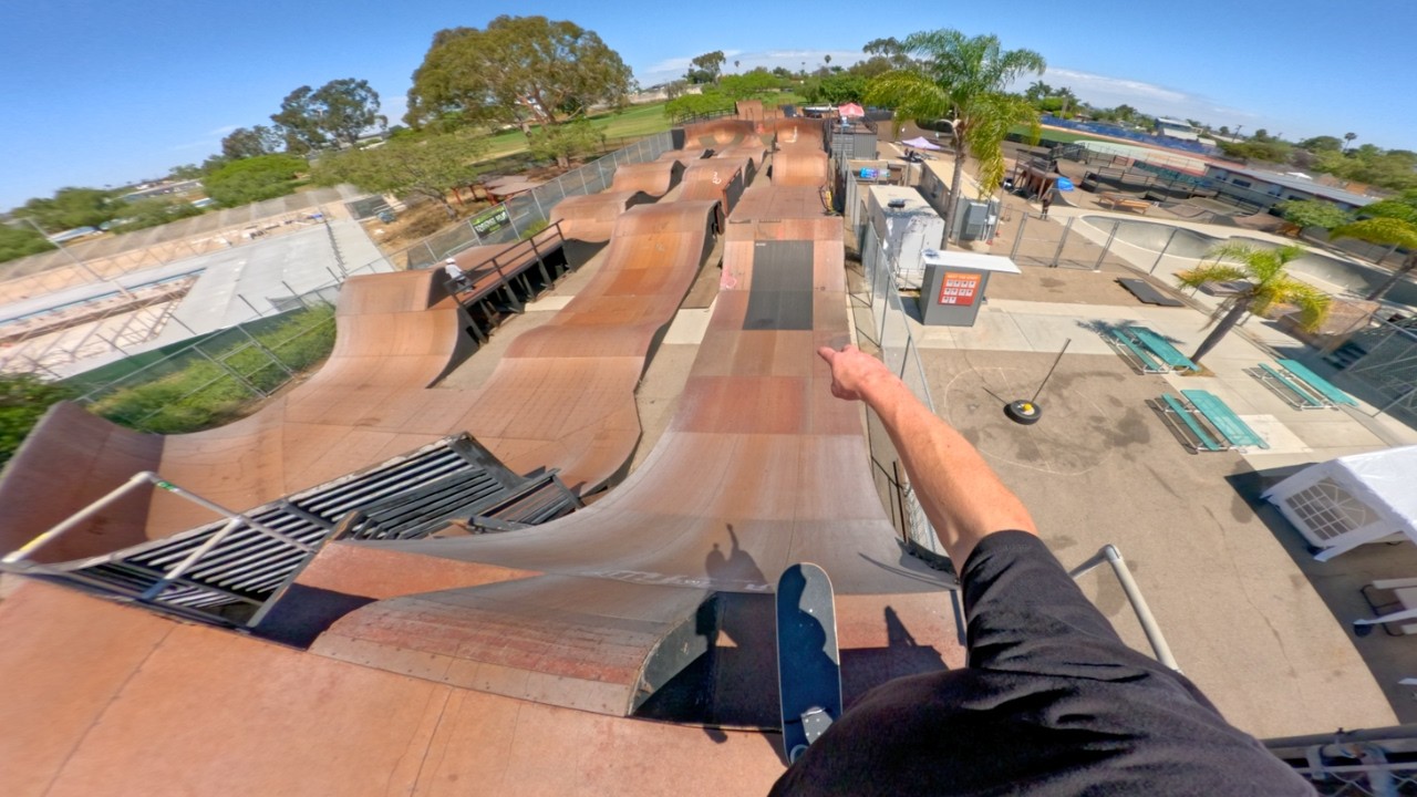 Looking down the winding wooden Skatercross ramp before dropping in, skateboard in hand